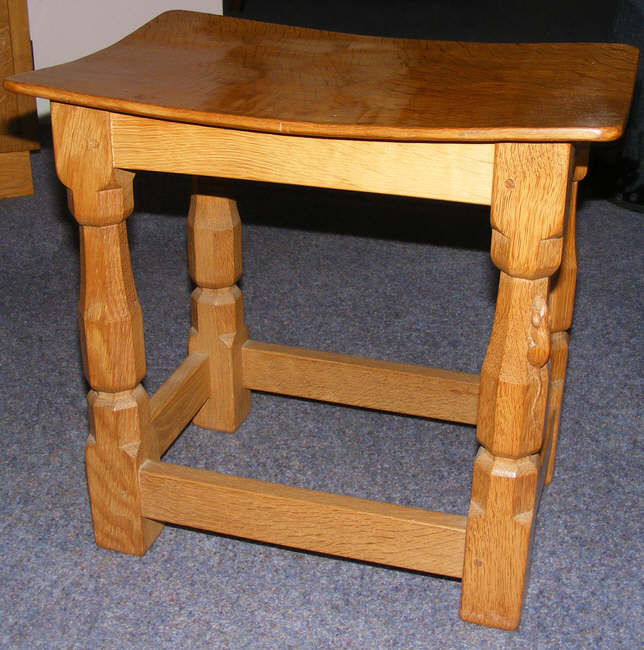 A Robert Thompson stool, with a curved wooden top. 